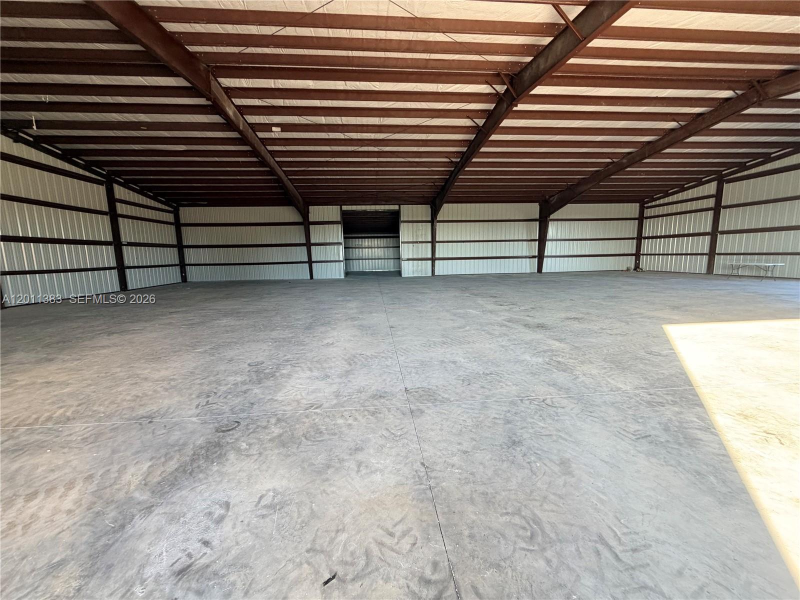 This is a large, open-concept metal warehouse with a concrete floor and exposed steel beams — 5601 SW 210th Ter, Southwest Ranches FL 33332, SOUTHWEST RANCHES, FL