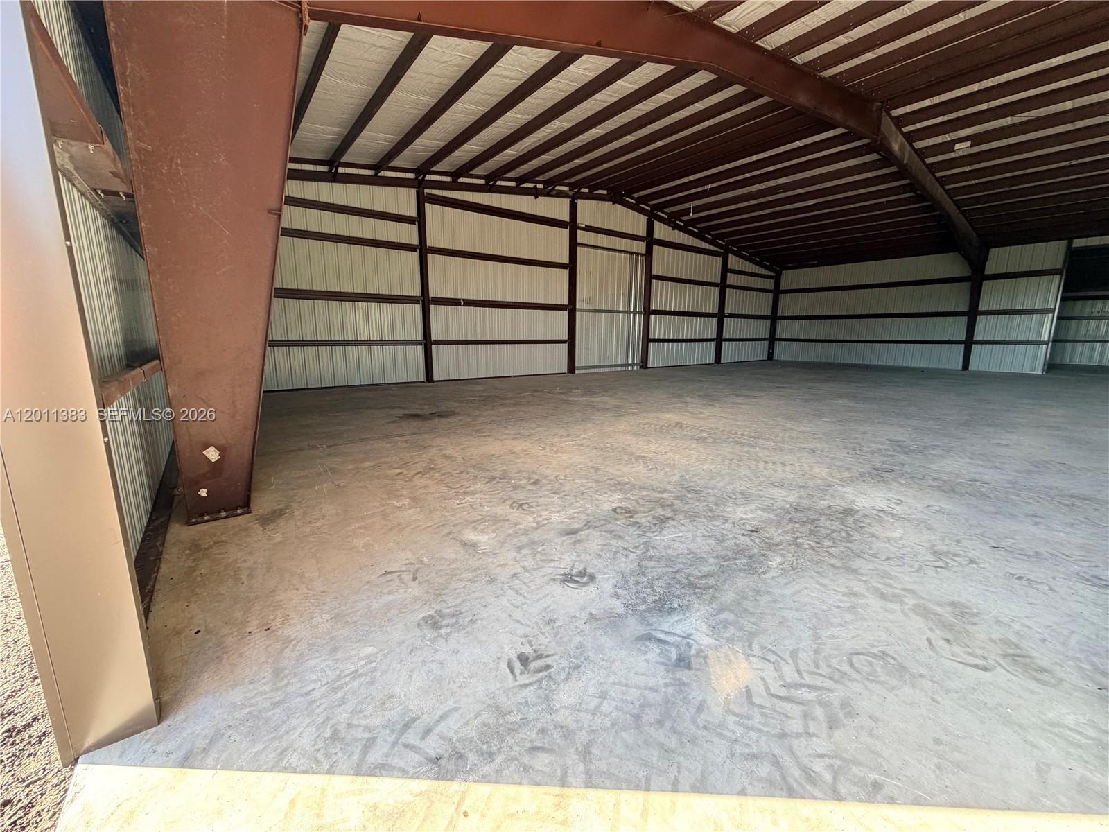 This is an interior view of a large, open-concept metal warehouse with concrete flooring — 5601 SW 210th Ter, Southwest Ranches FL 33332, SOUTHWEST RANCHES, FL