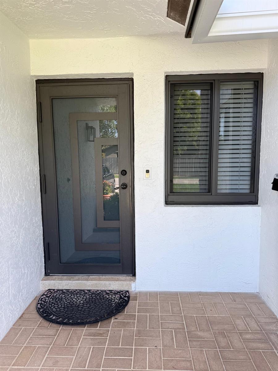 A front entryway featuring a dark-framed glass door, a window with blinds, and tiled flooring — 8843 SW 16th Street, Boca Raton FL 33433, BOCA RATON, FL