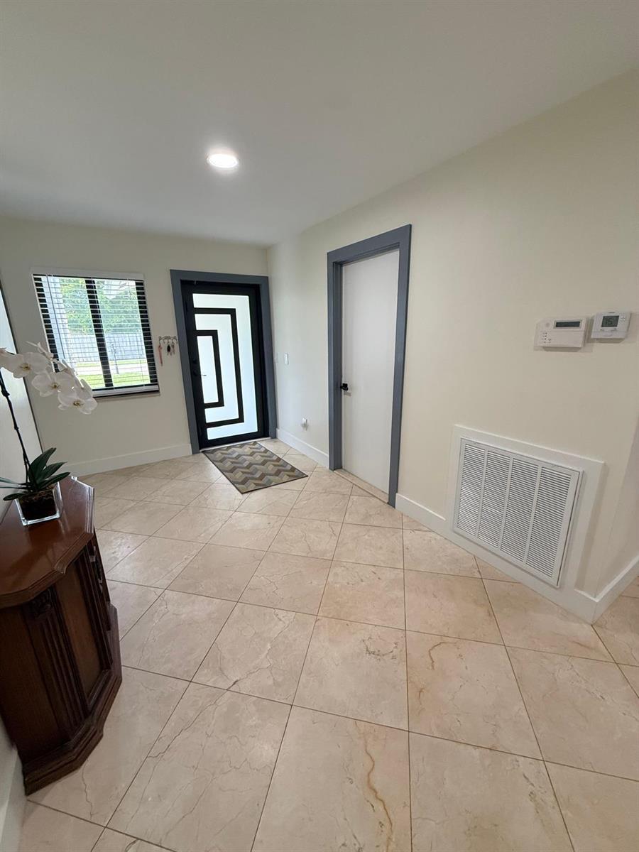 An entryway features beige tile flooring, a modern front door, and a white interior door — 8843 SW 16th Street, Boca Raton FL 33433, BOCA RATON, FL