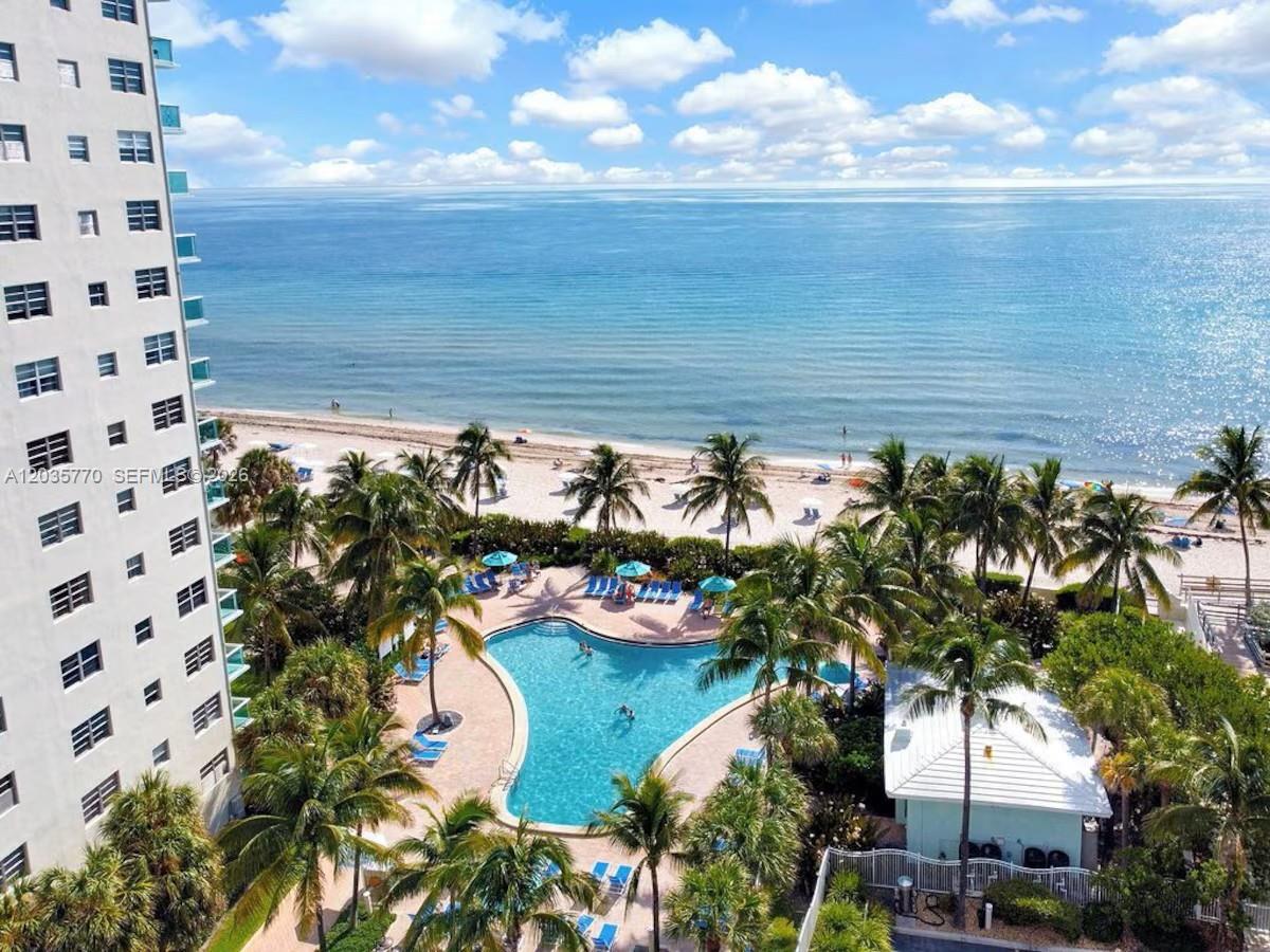 An aerial view of a swimming pool surrounded by palm trees next to a beach — 3901 S Ocean Dr # 14U, Hollywood FL 33019, HOLLYWOOD, FL