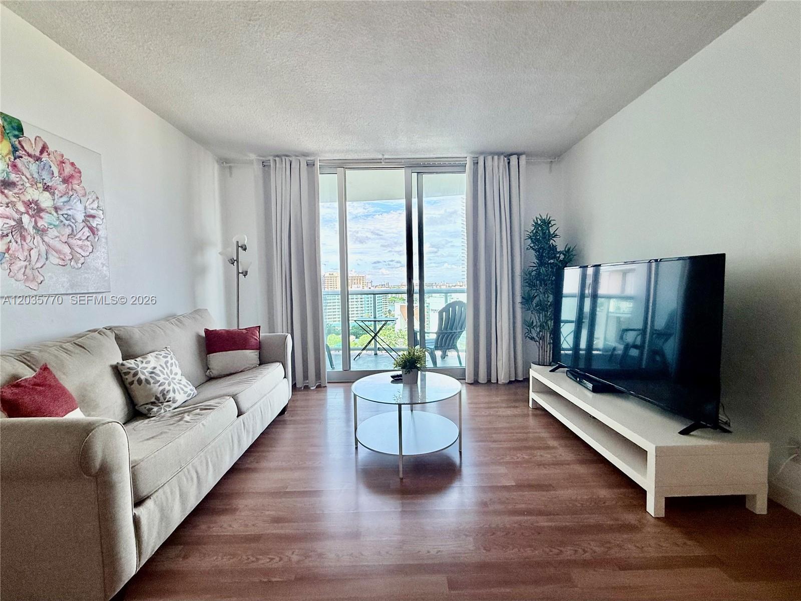 A living room features a beige sofa, a glass coffee table, and a television console — 3901 S Ocean Dr # 14U, Hollywood FL 33019, HOLLYWOOD, FL