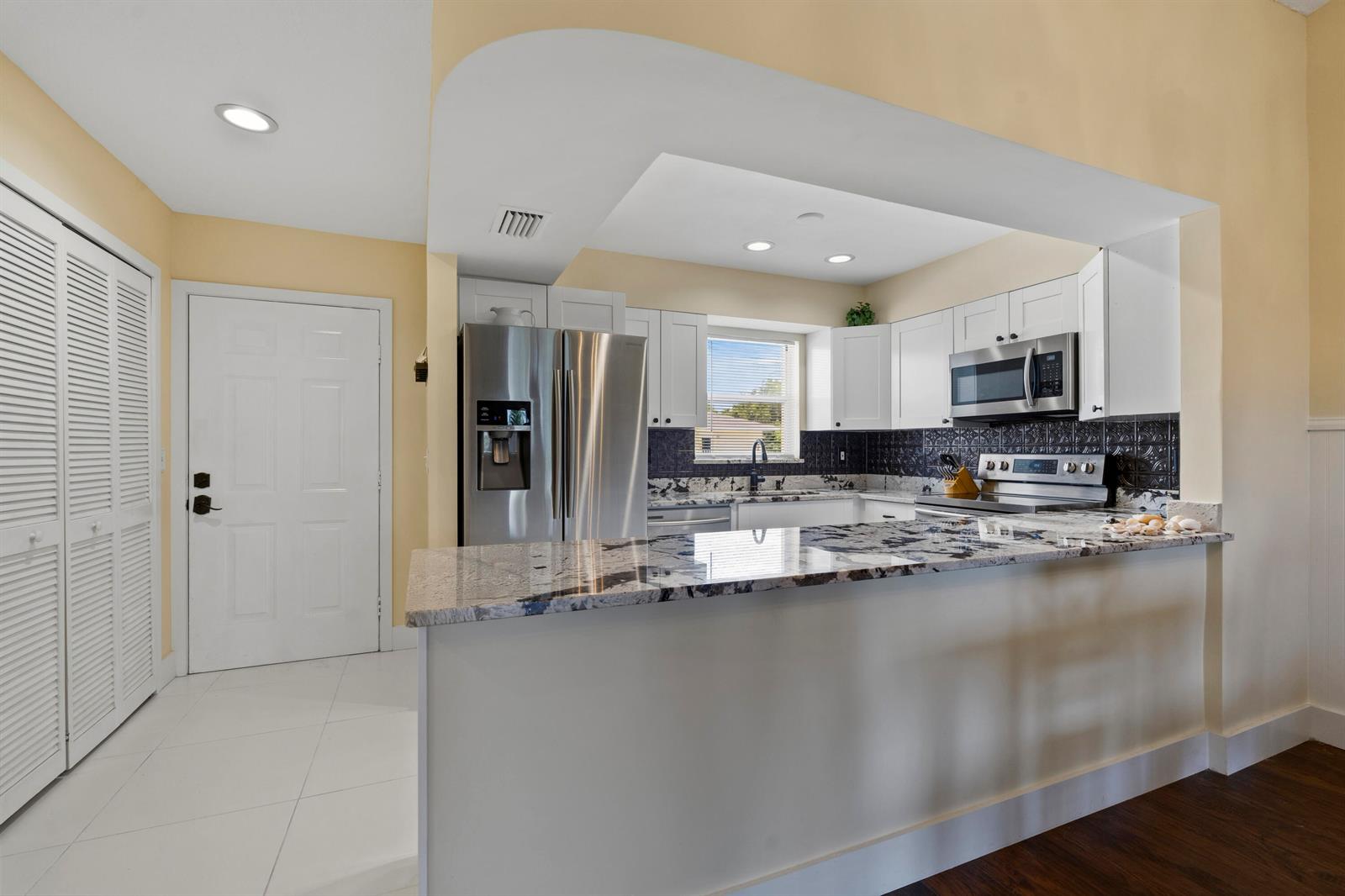 A kitchen features white cabinets, stainless steel appliances, granite countertops, and a breakfast bar — 2950 SE Ocean Boulevard # 6, Stuart FL 34996, STUART, FL
