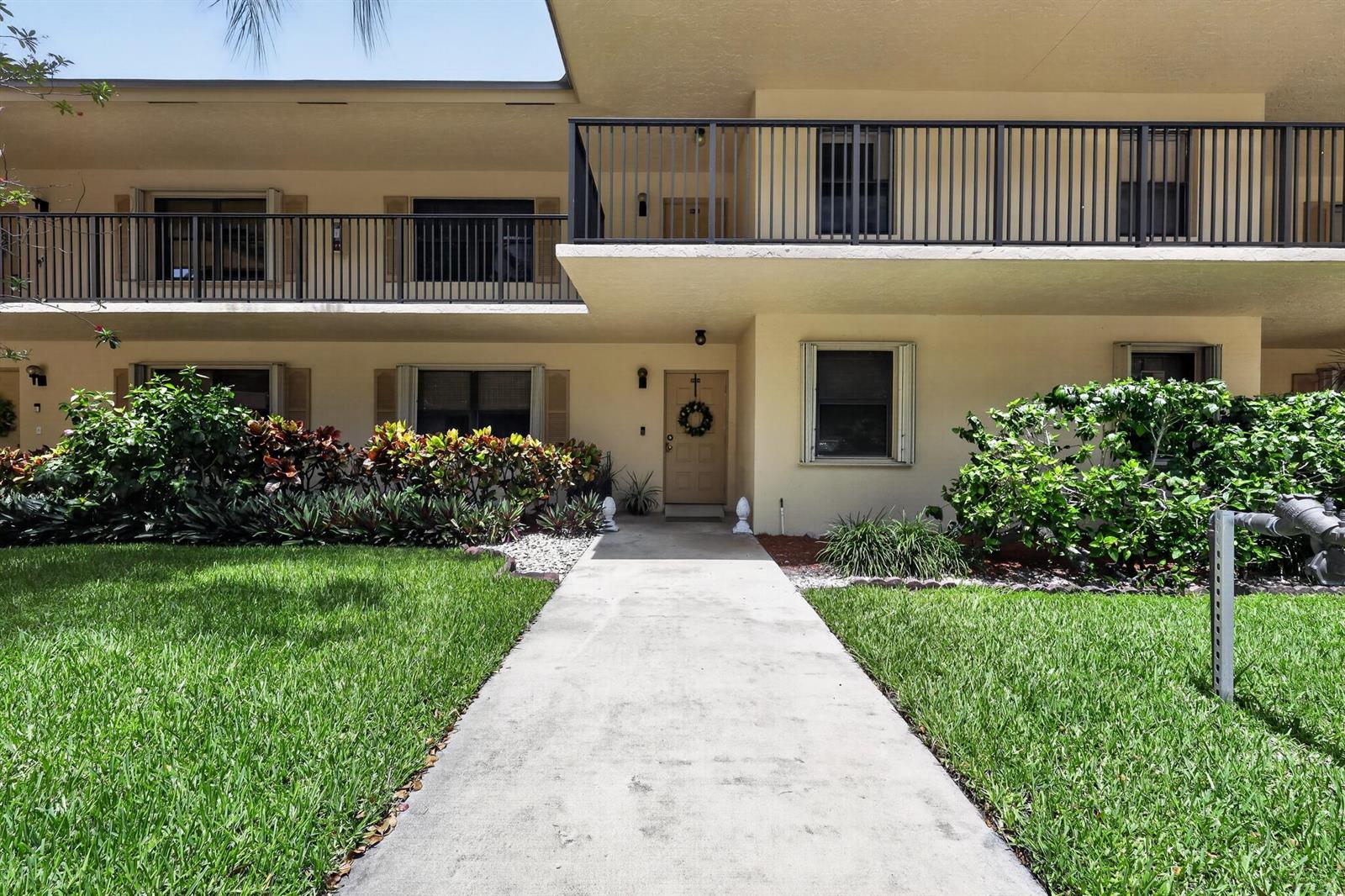 A two-story apartment building exterior features a concrete walkway leading to a central entrance — 2898 SW 22nd Circle # 231c, Delray Beach FL 33445, DELRAY BEACH, FL