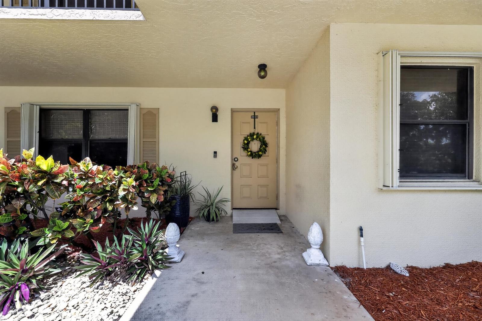 A beige exterior entryway features a front door with a wreath, windows, and landscaping — 2898 SW 22nd Circle # 231c, Delray Beach FL 33445, DELRAY BEACH, FL