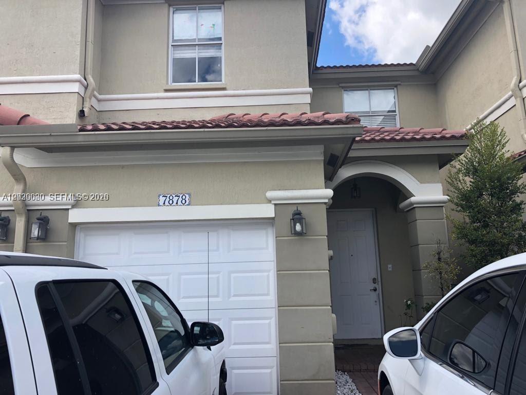 A two-story stucco townhouse features a white garage door, a tiled roof, and an entryway — 7878 NW 110th Ave, Doral FL 33178, DORAL, FL