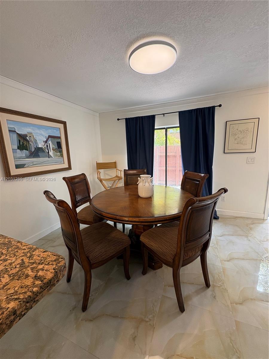 A dining room features a round wooden table, four chairs, and a large framed painting — 7104 SW 114th Pl # A, Miami FL 33173, MIAMI, FL