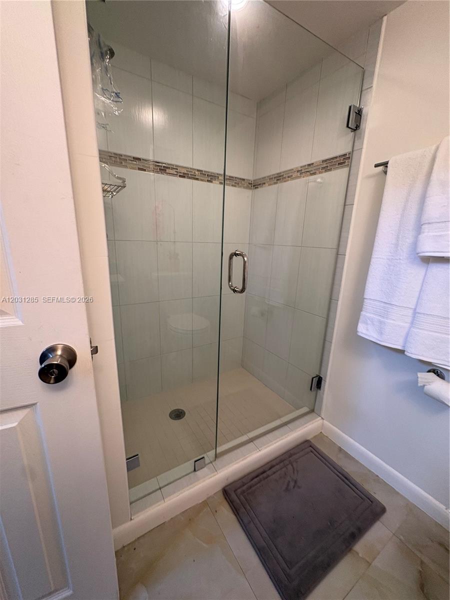 A bathroom features a glass-enclosed walk-in shower with white tile walls and a mosaic accent — 7104 SW 114th Pl # A, Miami FL 33173, MIAMI, FL
