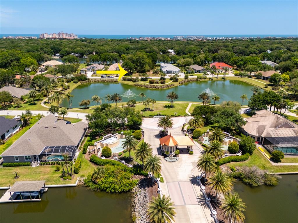 An aerial view shows a gated community entrance, a lake with fountains, and surrounding houses — 66 OLD OAK DRIVE S, PALM COAST, FL