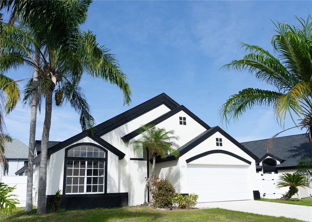 A white house with black trim and a two-car garage sits under a blue sky — 2319 ISLAND CLUB WAY, ORLANDO, FL