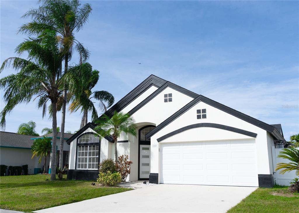 A single-story house with white stucco walls, black trim, and a two-car garage — 2319 ISLAND CLUB WAY, ORLANDO, FL