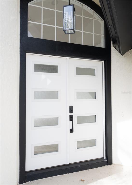A white double front door with four rectangular glass panels sits under a black archway — 2319 ISLAND CLUB WAY, ORLANDO, FL