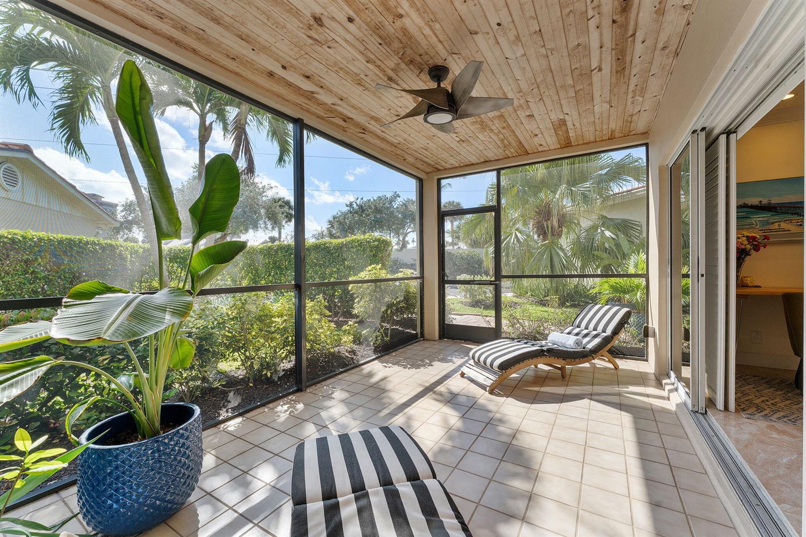 A screened-in patio features a wood-plank ceiling, tiled floor, lounge chairs, and a potted plant — 4161 S Us Highway 1 # G1, Jupiter FL 33477, JUPITER, FL