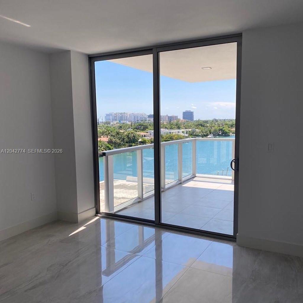 A room with light-colored tile flooring features a large sliding glass door opening to a balcony — 9521 E Bay Harbor Dr # 605, Bay Harbor Islands FL 33154, BAY HARBOR ISLANDS, FL