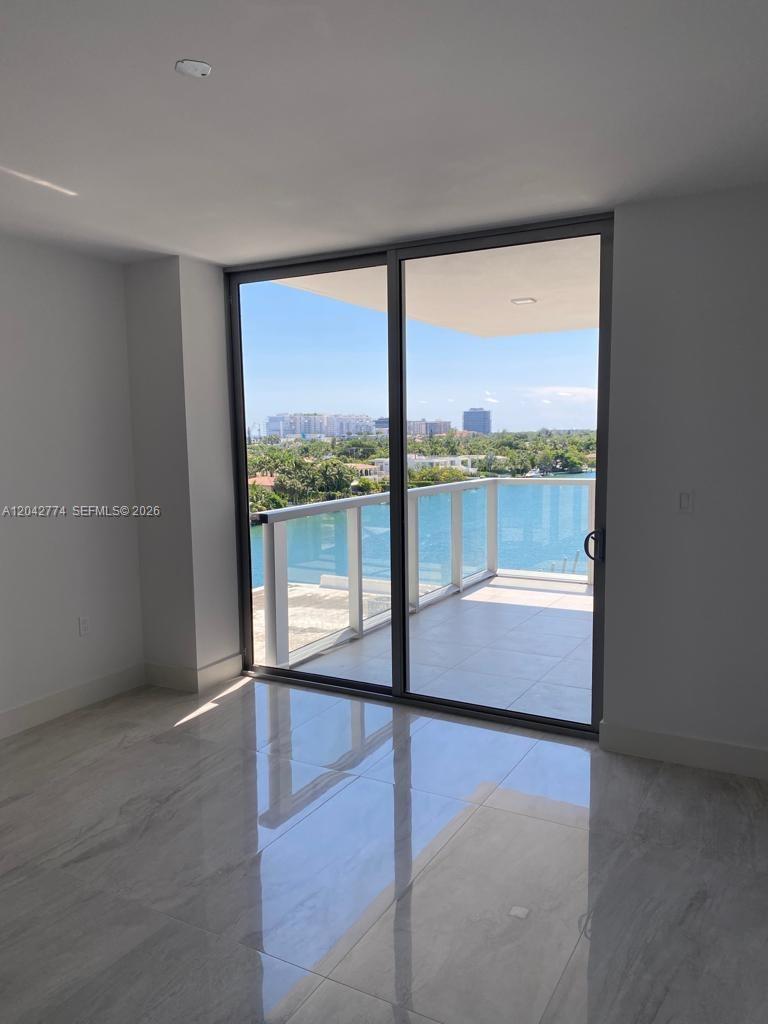 A room with light-colored tile flooring features a sliding glass door opening to a balcony — 9521 E Bay Harbor Dr # 605, Bay Harbor Islands FL 33154, BAY HARBOR ISLANDS, FL