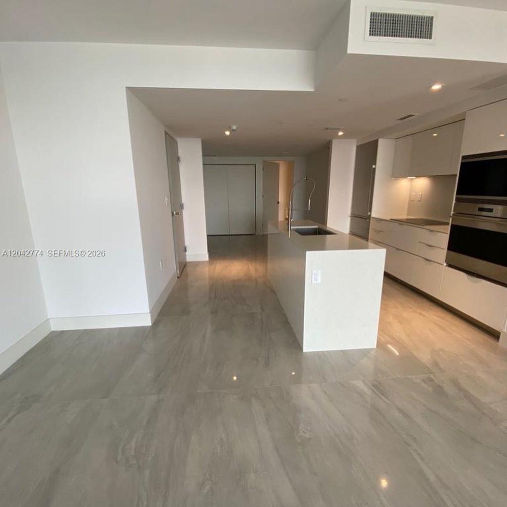 A modern kitchen features a white island, light gray cabinetry, and polished tile flooring — 9521 E Bay Harbor Dr # 605, Bay Harbor Islands FL 33154, BAY HARBOR ISLANDS, FL