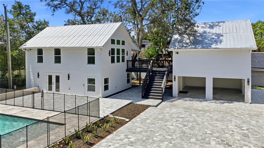 An exterior view of a white two-story house with a metal roof, pool, and garage — 1109 CHARLES STREET, CLEARWATER, FL