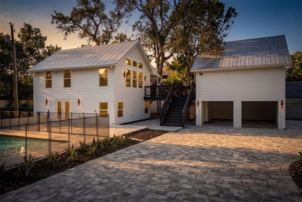 A white two-story house with a metal roof, pool, and detached garage at sunset — 1109 CHARLES STREET, CLEARWATER, FL