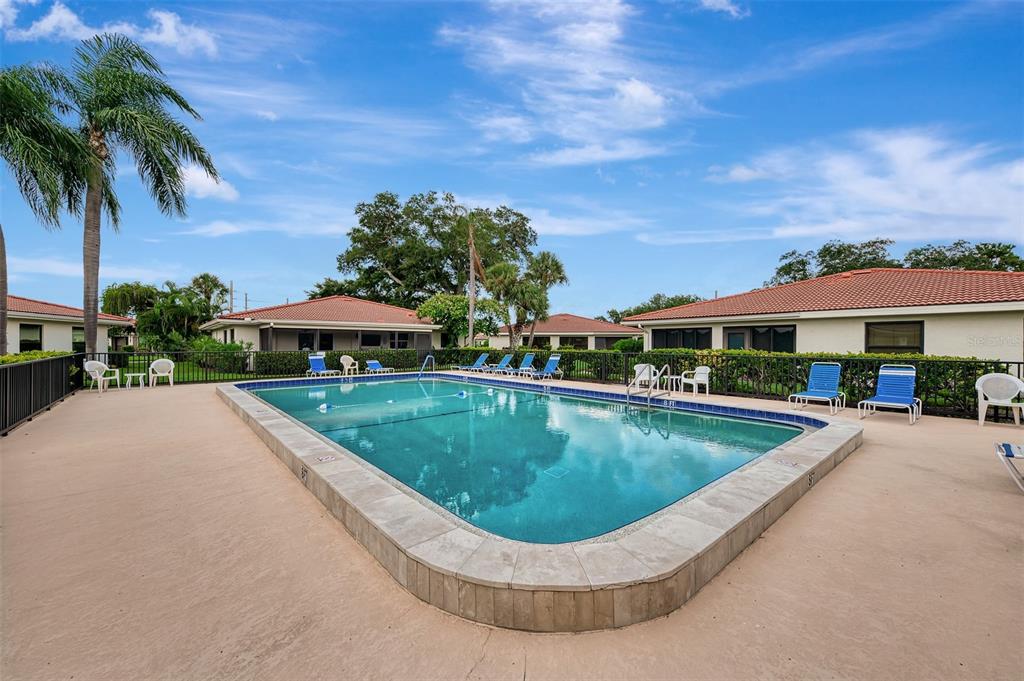 A rectangular swimming pool surrounded by a concrete deck and lounge chairs in a residential complex — 5103 GREENCROFT ROAD, SARASOTA, FL