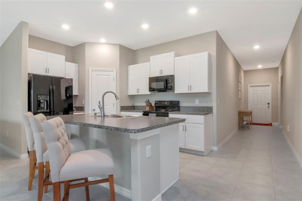 A kitchen features white cabinets, granite countertops, a black refrigerator, and a breakfast bar island — 11527 SAGE CANYON DRIVE, RIVERVIEW, FL