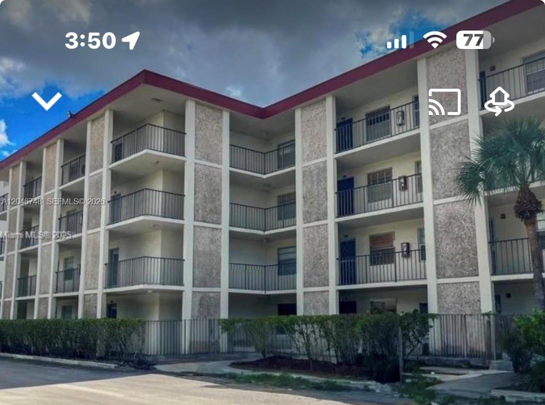A multi-story apartment building features exterior balconies and a textured concrete facade — LAUDERDALE LAKES, FL