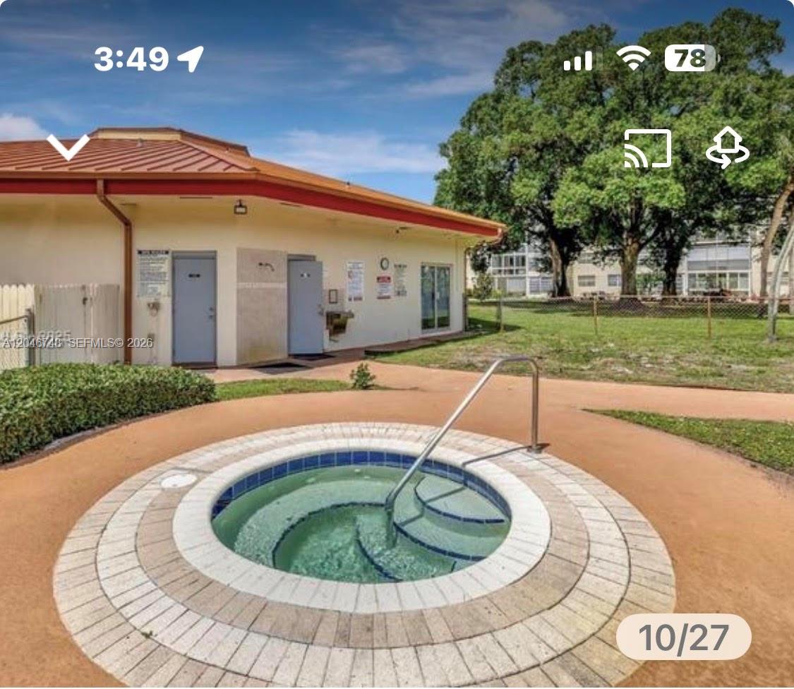 A circular hot tub with a metal handrail sits on a patio near a building — LAUDERDALE LAKES, FL