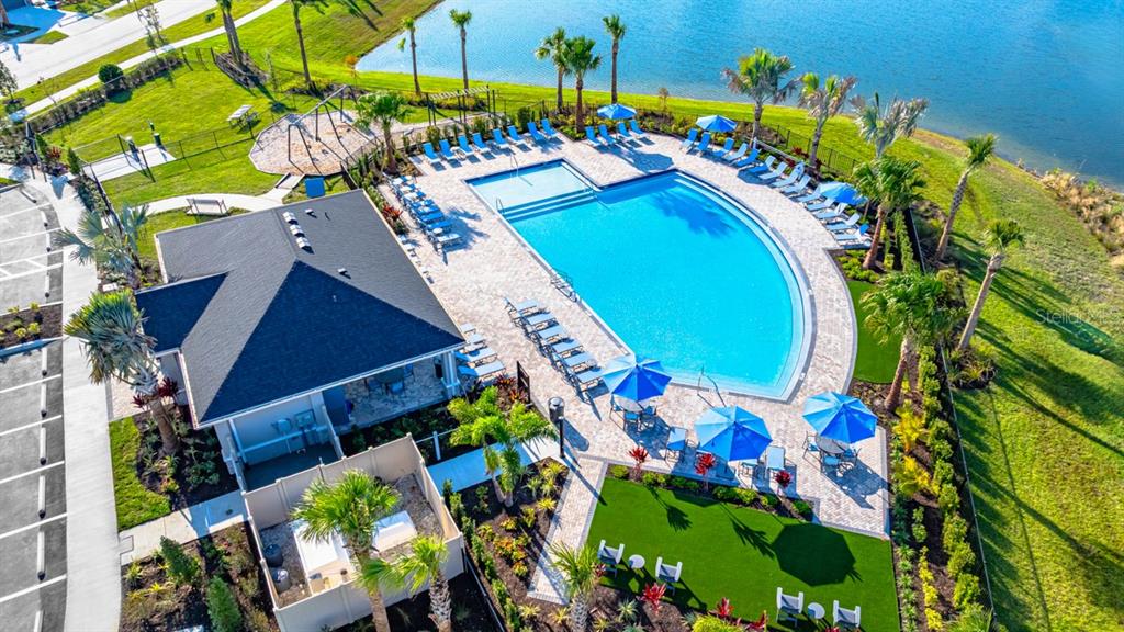 An aerial view shows a community swimming pool, clubhouse, playground, and lake in a neighborhood — 846 STEEL DRIVE, APOLLO BEACH, FL