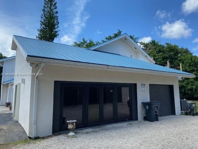 A white building with a blue metal roof features black folding glass doors and a garage — 4450 S Jog Road, FL 33467, FL