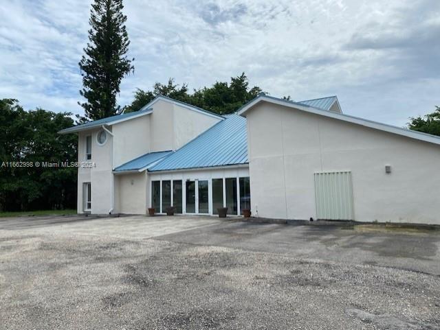 A two-story building with a blue metal roof stands above a gravel parking lot — 4450 S Jog Road, FL 33467, FL