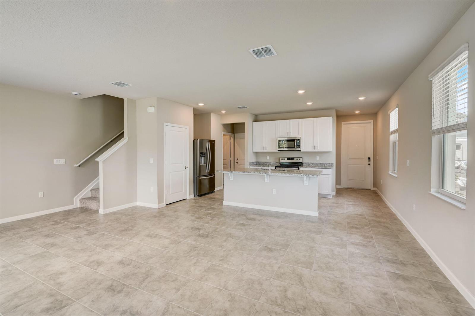 An open-concept kitchen and living area features tile flooring, white cabinetry, and a center island — 5728 SE Edgewater Circle, Stuart FL 34997, STUART, FL