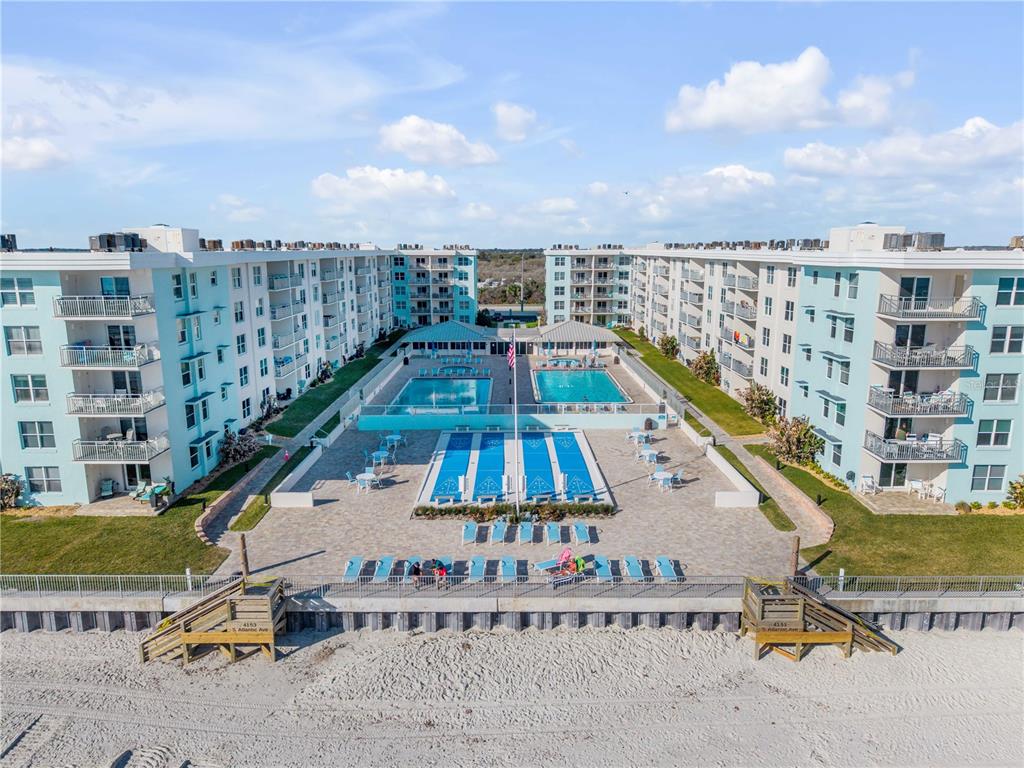 An aerial view of a beachfront apartment complex with multiple swimming pools and lounge chairs — 4153 S ATLANTIC AVENUE UNIT 1170, NEW SMYRNA BEACH, FL