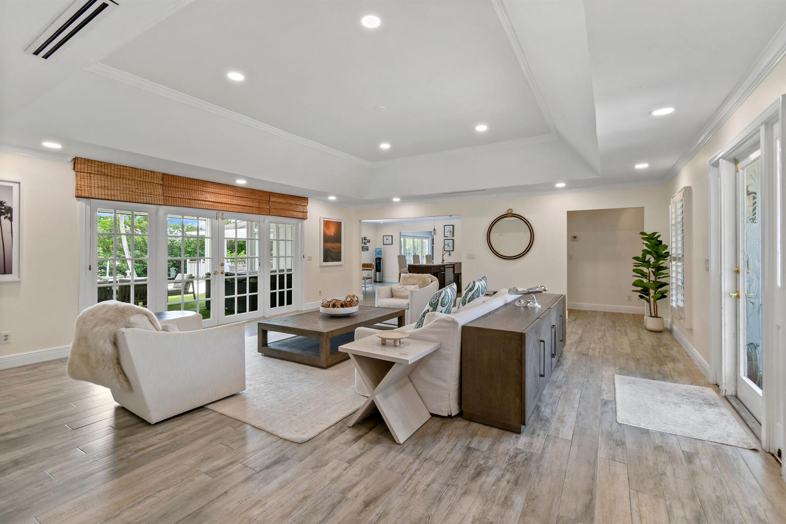 A bright living room features light wood-look flooring, a tray ceiling, and glass doors to a patio — 938 Turner Quay, Jupiter FL 33458, JUPITER, FL