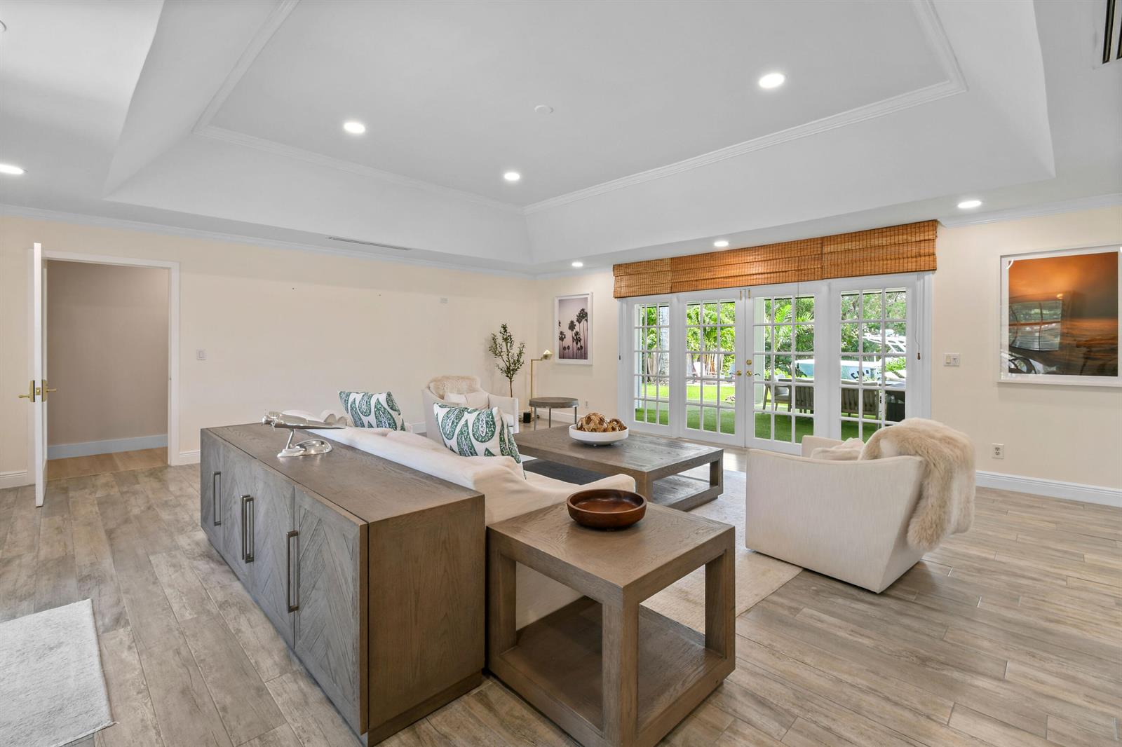 A living room features a tray ceiling, wood-look tile floors, and glass doors opening to a yard — 938 Turner Quay, Jupiter FL 33458, JUPITER, FL