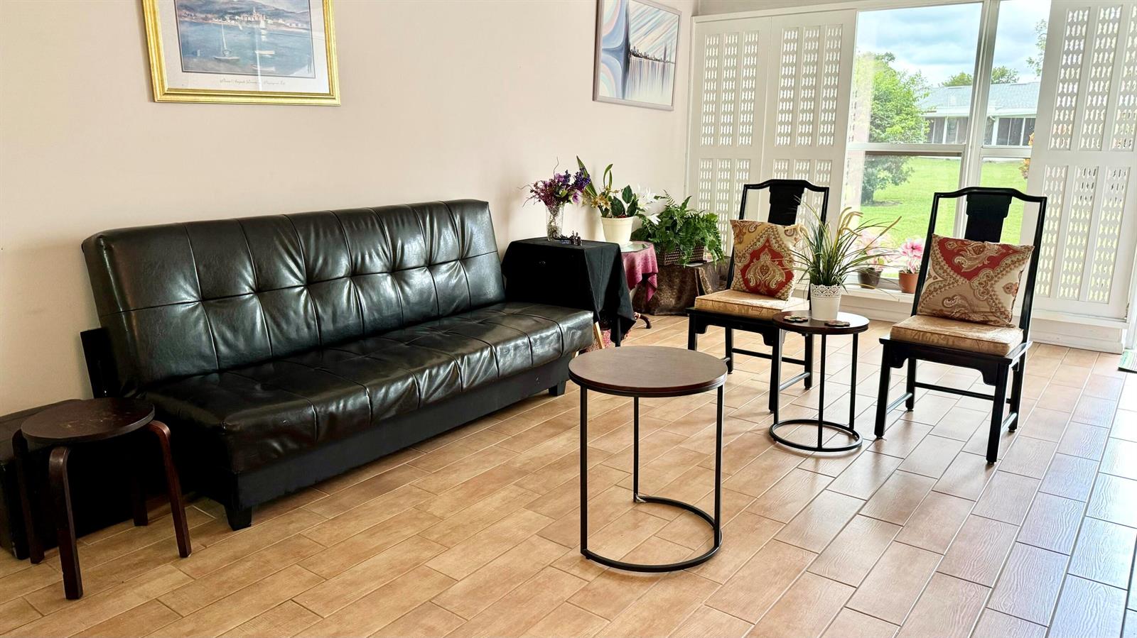 A living room features a black sofa, two chairs with patterned pillows, and tile flooring — 1551 NW 20th Avenue # 102, Delray Beach FL 33445, DELRAY BEACH, FL