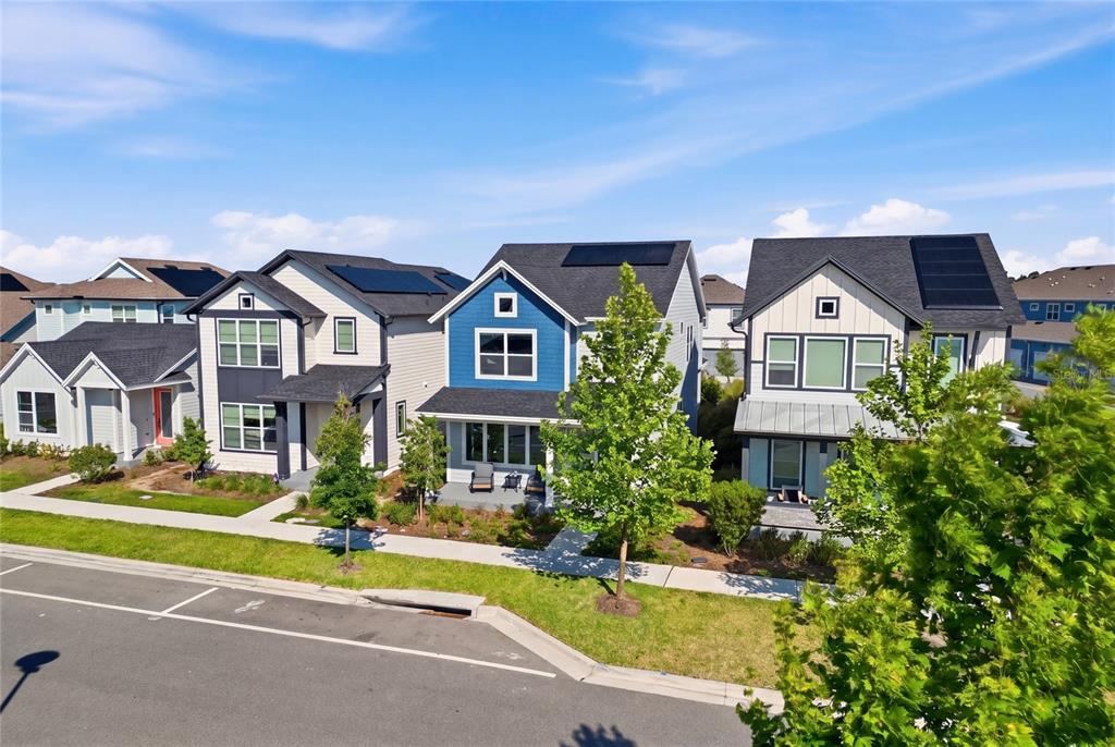 An aerial view shows three modern suburban houses with solar panels and front porches — 3007 MIRAGE PLACE, ST CLOUD, FL