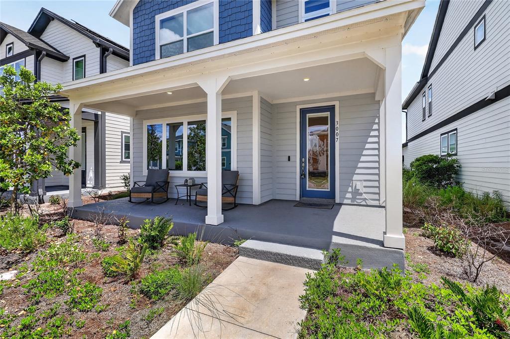 A front porch with a blue door and two rocking chairs sits before a house — 3007 MIRAGE PLACE, ST CLOUD, FL