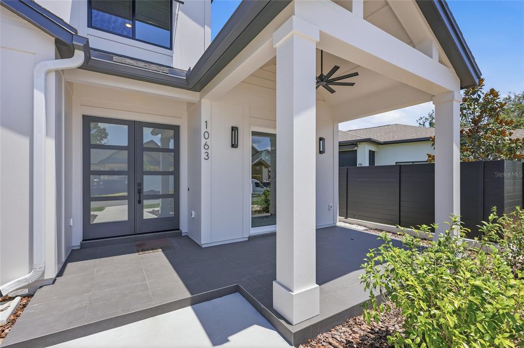 A modern home entrance features a covered porch with gray tile flooring and double doors — 1063 SW 135 DRIVE, NEWBERRY, FL