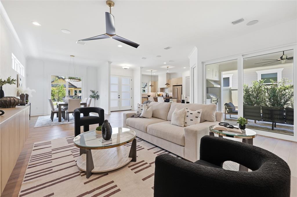 A bright, open-concept living room features a beige sofa, two black chairs, and wood flooring — 1063 SW 135 DRIVE, NEWBERRY, FL