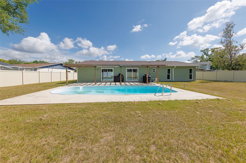 A light green house with a backyard swimming pool and a covered patio area — 4228 BRIARBERRY LANE, TAMPA, FL