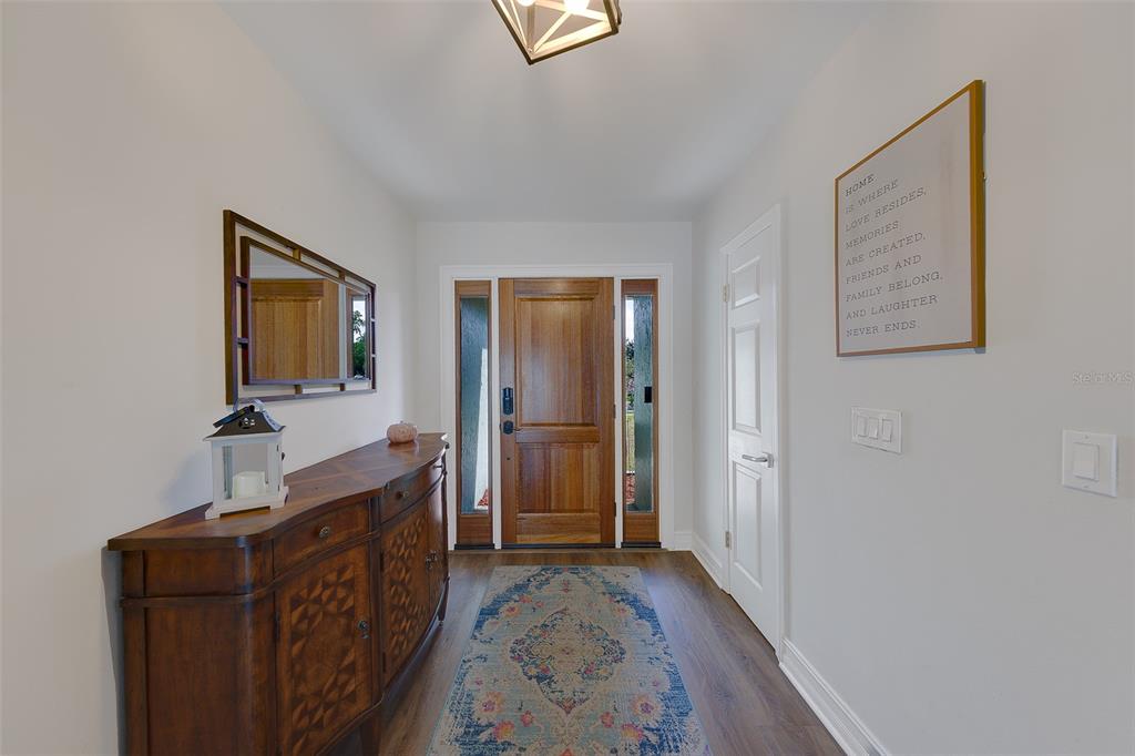 A wooden entryway features a console table, a mirror, and a front door with sidelights — 4228 BRIARBERRY LANE, TAMPA, FL