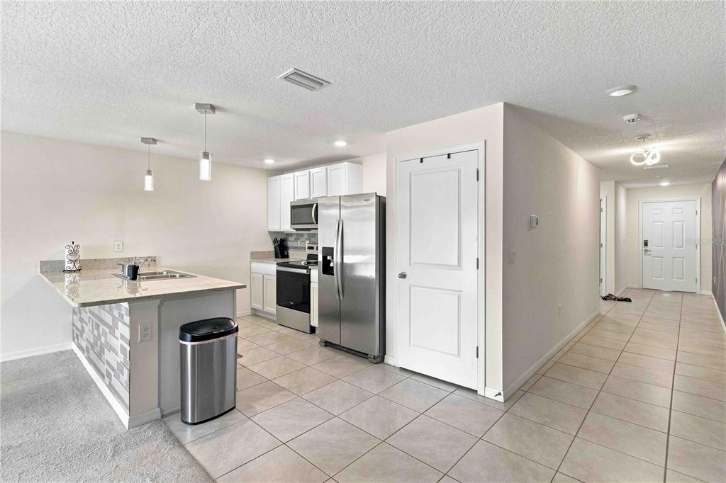 A kitchen with stainless steel appliances, white cabinets, and a breakfast bar overlooks a hallway — 2496 RIM DRIVE, SPRING HILL, FL