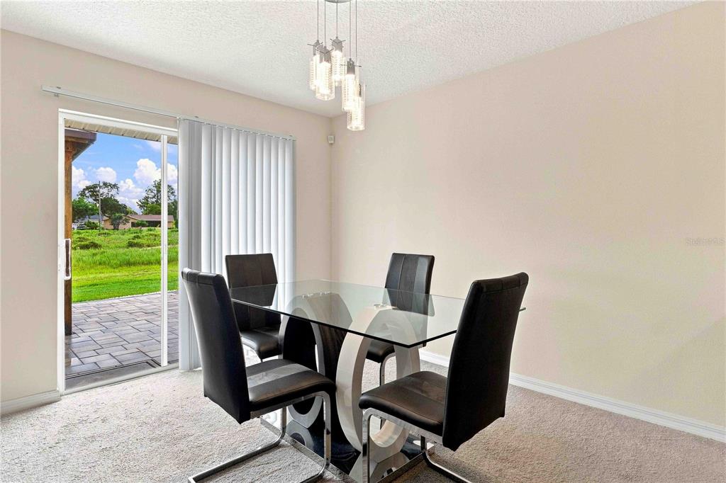 A dining area features a glass table, four black chairs, and a sliding glass door — 2496 RIM DRIVE, SPRING HILL, FL