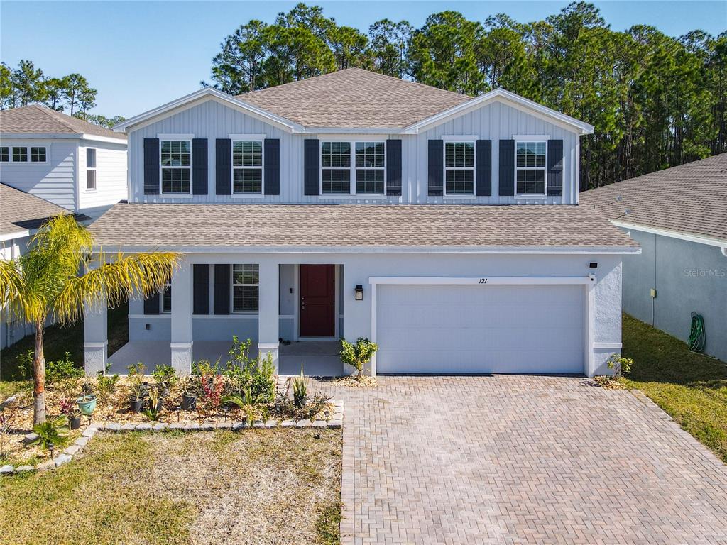 A two-story house with a light gray exterior, a red front door, and a paved driveway — 121 EAGLE HARBOR WAY WAY, DAYTONA BEACH, FL