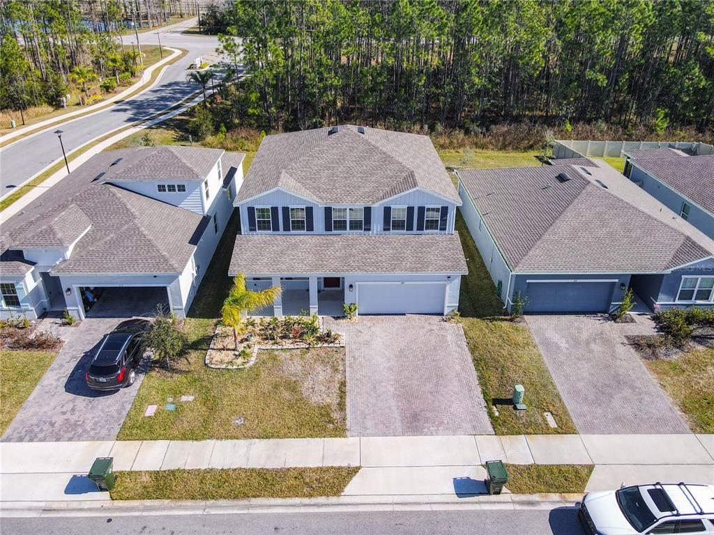 An aerial view shows three suburban houses with paved driveways and lawns along a street — 121 EAGLE HARBOR WAY WAY, DAYTONA BEACH, FL