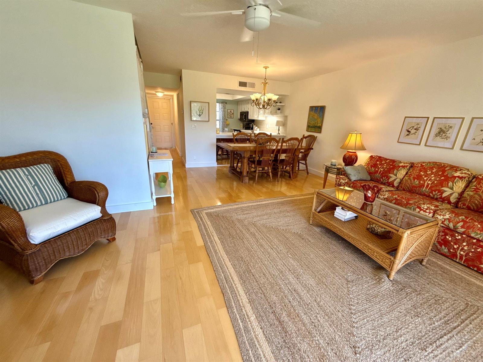 A living room with hardwood floors, a wicker chair, and a floral sofa — 18390 SE Wood Haven Lane, Jupiter FL 33469, JUPITER, FL