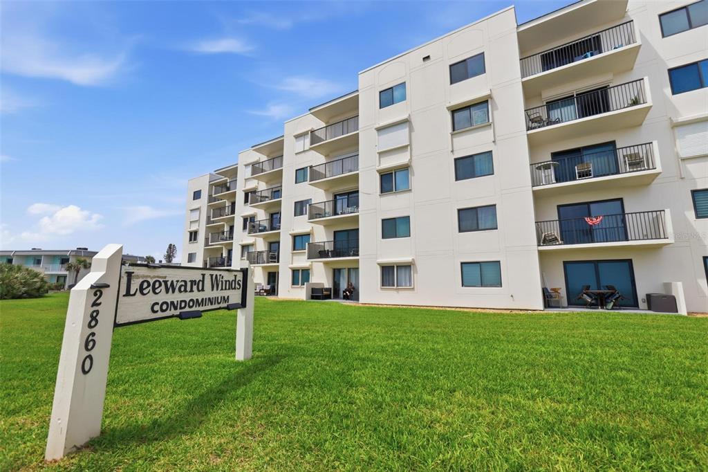 A multi-story white condominium building stands behind a sign on a grassy lawn — 2860 OCEAN SHORE BOULEVARD UNIT 3030, ORMOND BY THE SEA, FL