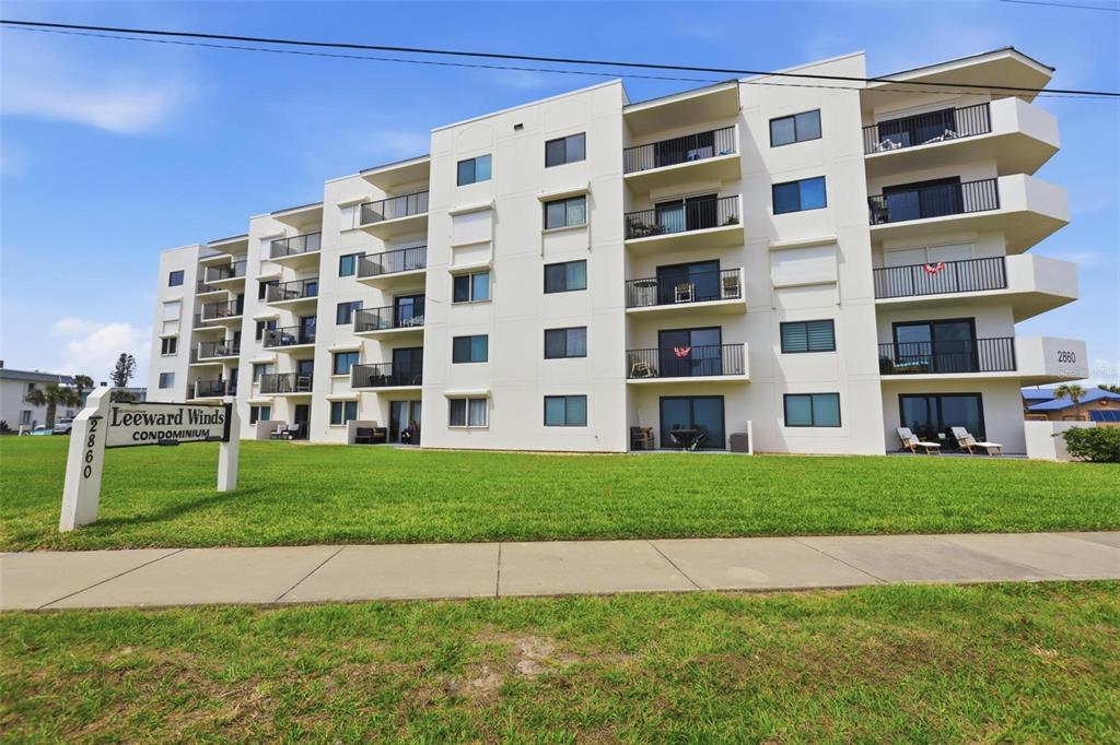 A multi-story white condominium building stands behind a grassy lawn and a sidewalk — 2860 OCEAN SHORE BOULEVARD UNIT 3030, ORMOND BY THE SEA, FL