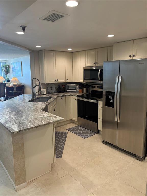 A kitchen features cream cabinets, granite countertops, stainless steel appliances, and light tile flooring — 9650 S Ocean Drive S # 809, Jensen Beach FL 34957, JENSEN BEACH, FL