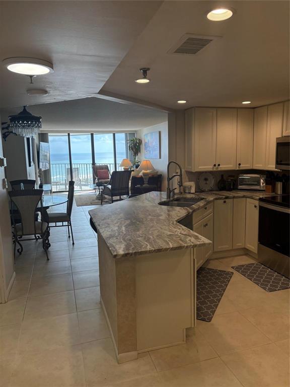 A kitchen with granite countertops and light cabinets opens to a dining area and balcony — 9650 S Ocean Drive S # 809, Jensen Beach FL 34957, JENSEN BEACH, FL