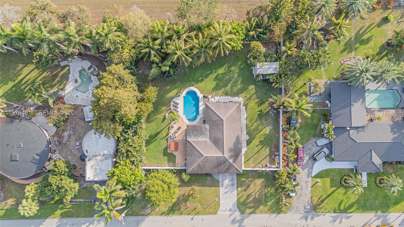 An aerial view shows a house with a pool, palm trees, and a circular structure — 11400 Tara Dr, Plantation FL 33325, PLANTATION, FL